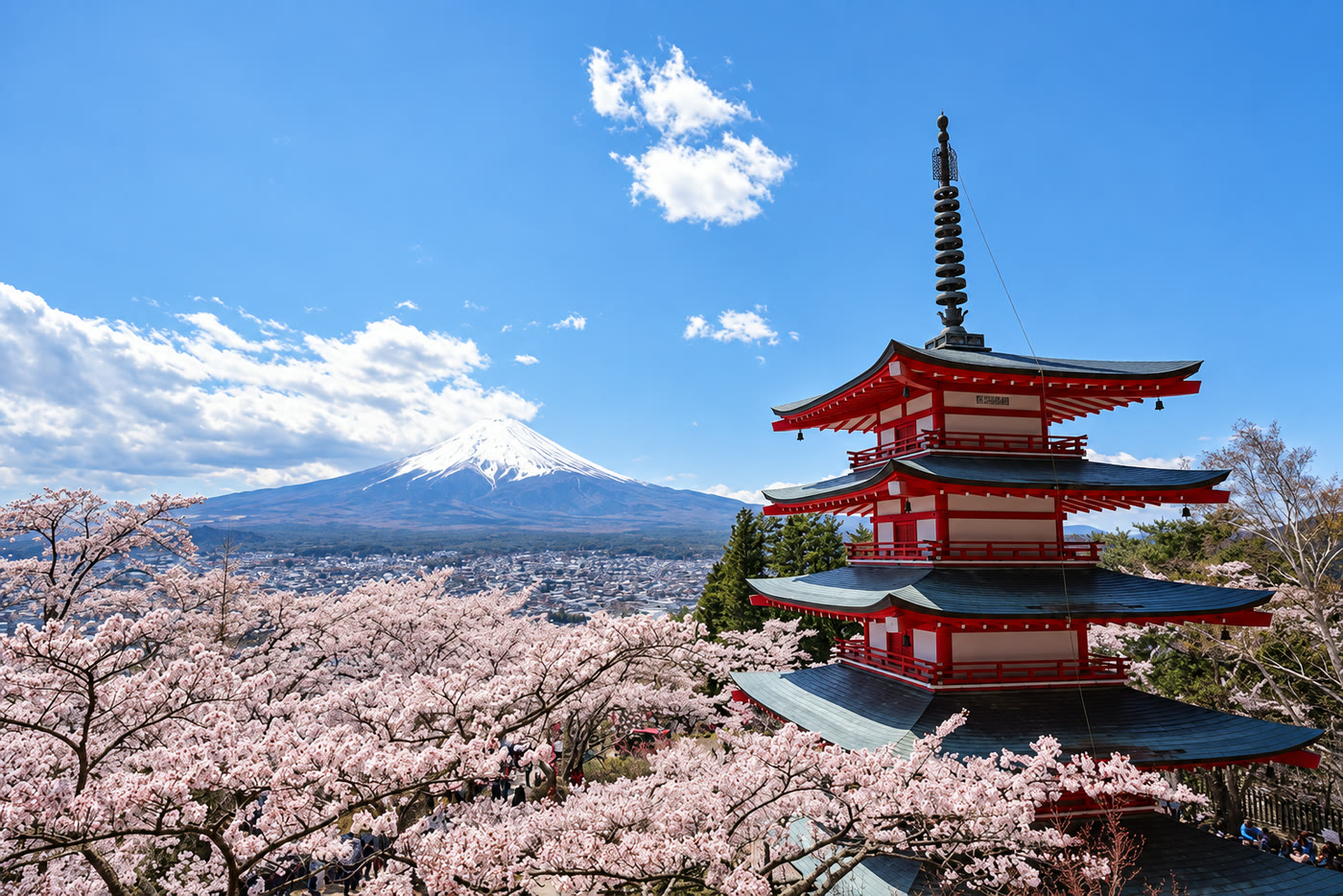 The vermilion five-storey pagoda at Arakurayama Sengen Park above cherry trees in bloom, with Mount Fuji beyond