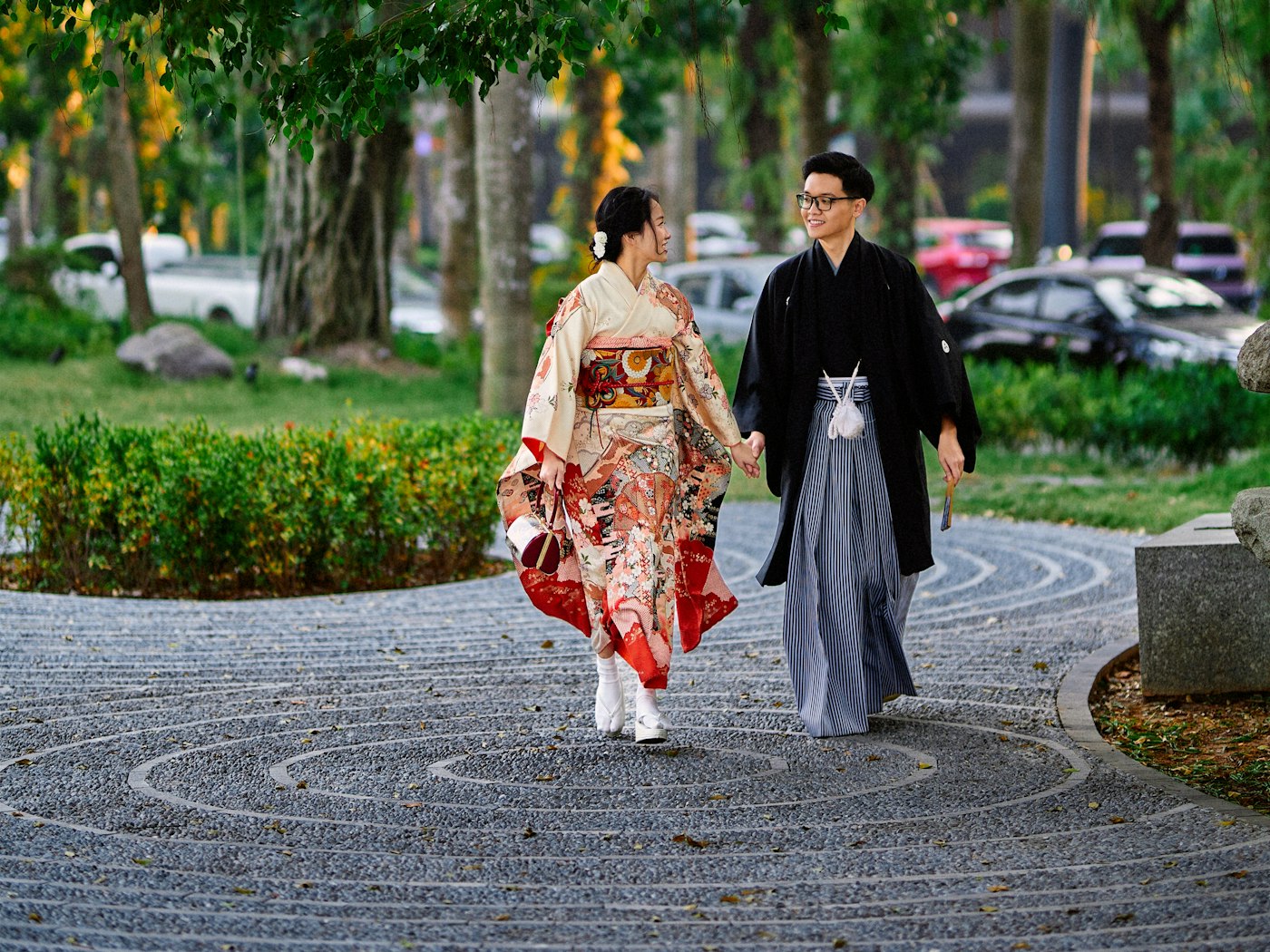 Couple in formal kimono walking side by side along a stone garden path