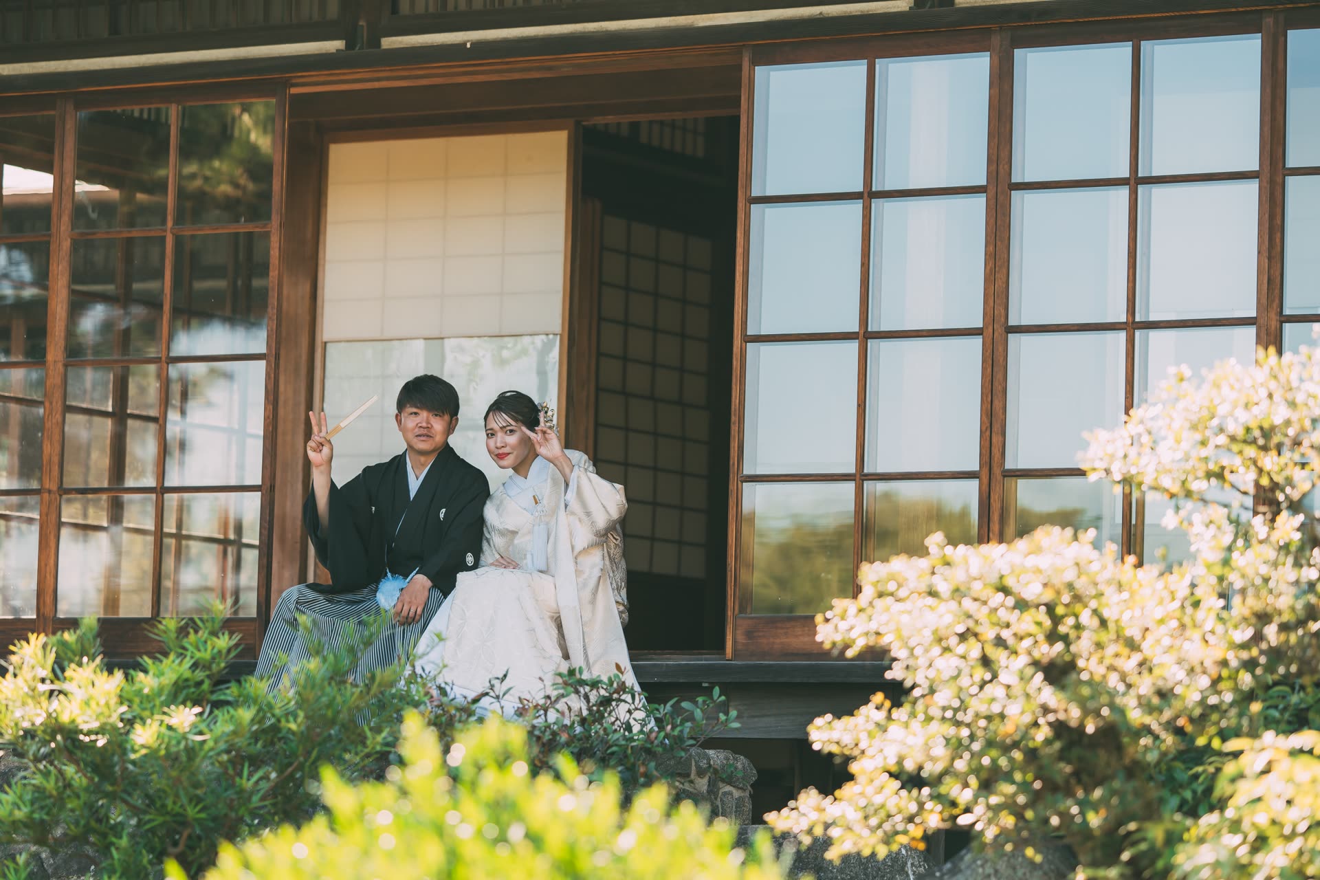 Couple in kimono laughing together on the engawa veranda of an old Japanese house