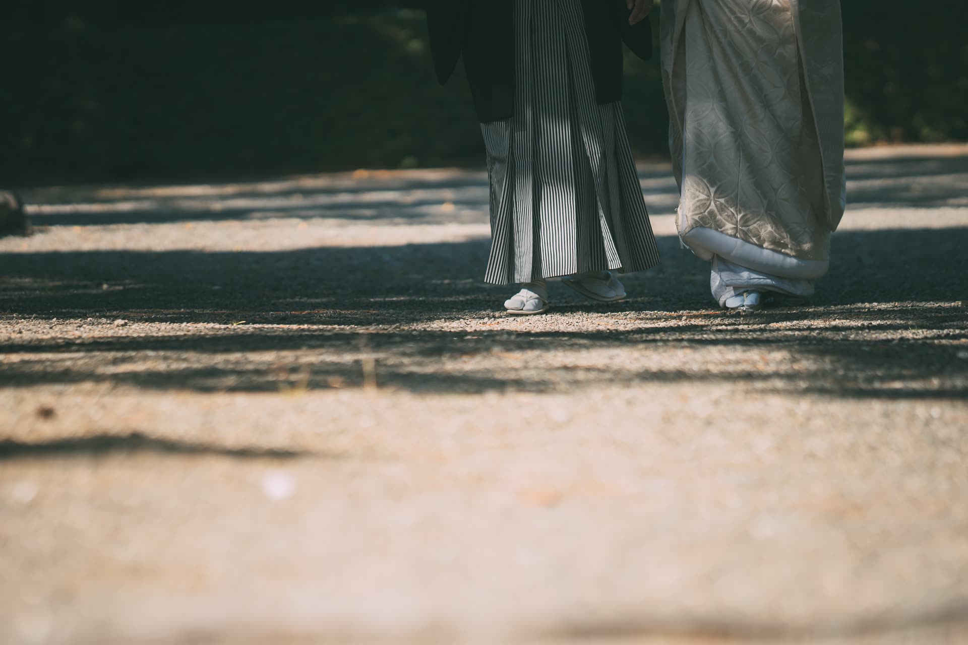 Detail of hakama and kimono hems as a couple walk a gravel garden path