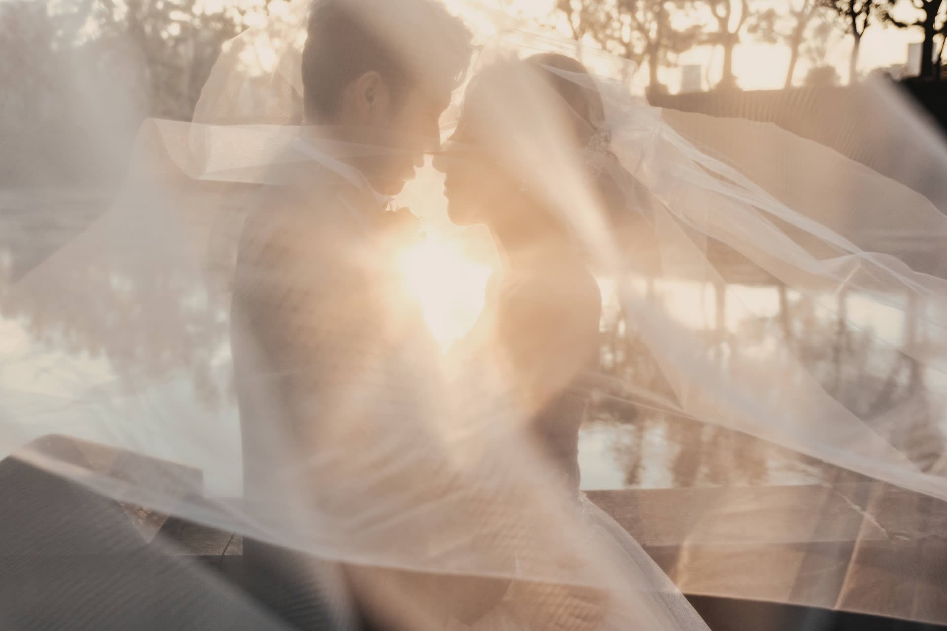 Bride and groom framed by a veil catching the low sun during a photoshoot in Japan