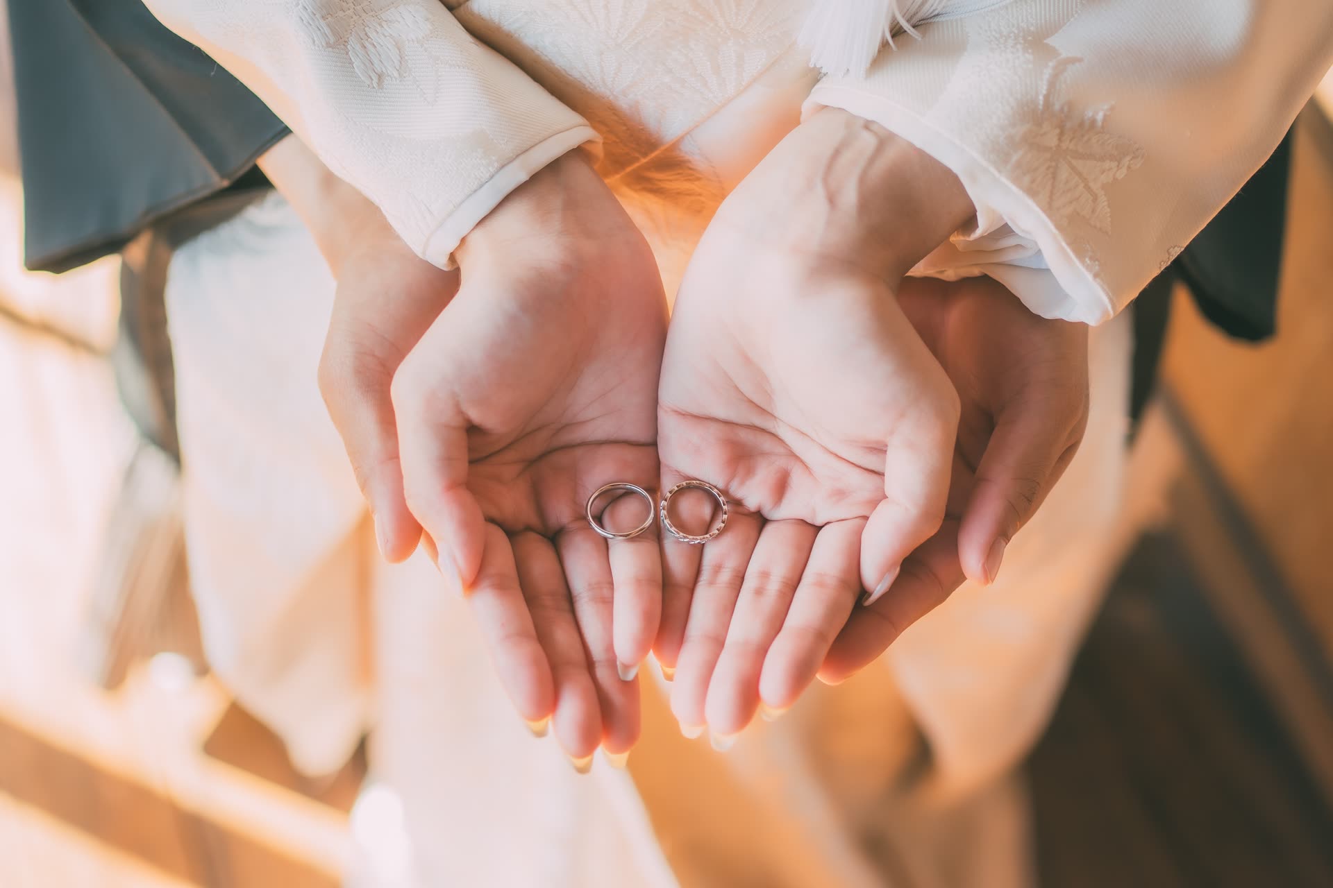 Wedding rings held in cupped hands above the white silk of a shiromuku kimono