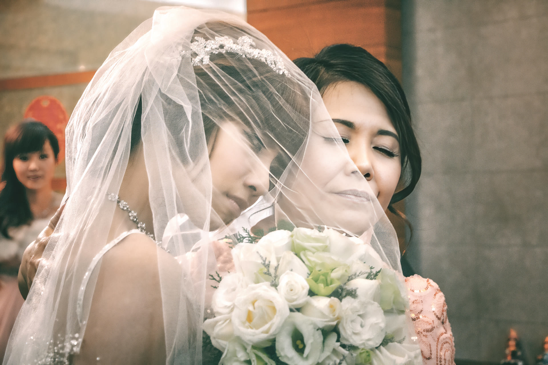 Bride under her veil embracing her mother on the wedding day