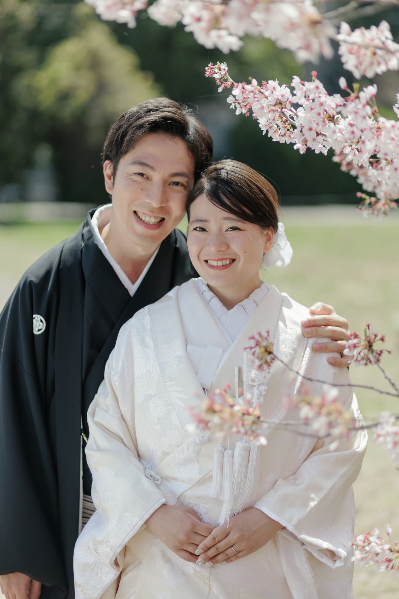 Close portrait of a smiling couple in kimono with a cherry branch in the foreground