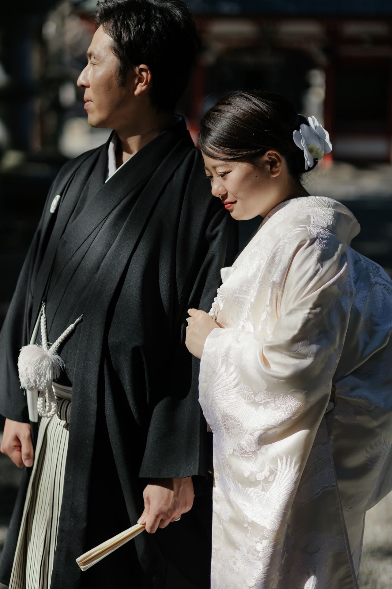 Close profile of the groom in montsuki and the bride in shiromuku in warm sunlight