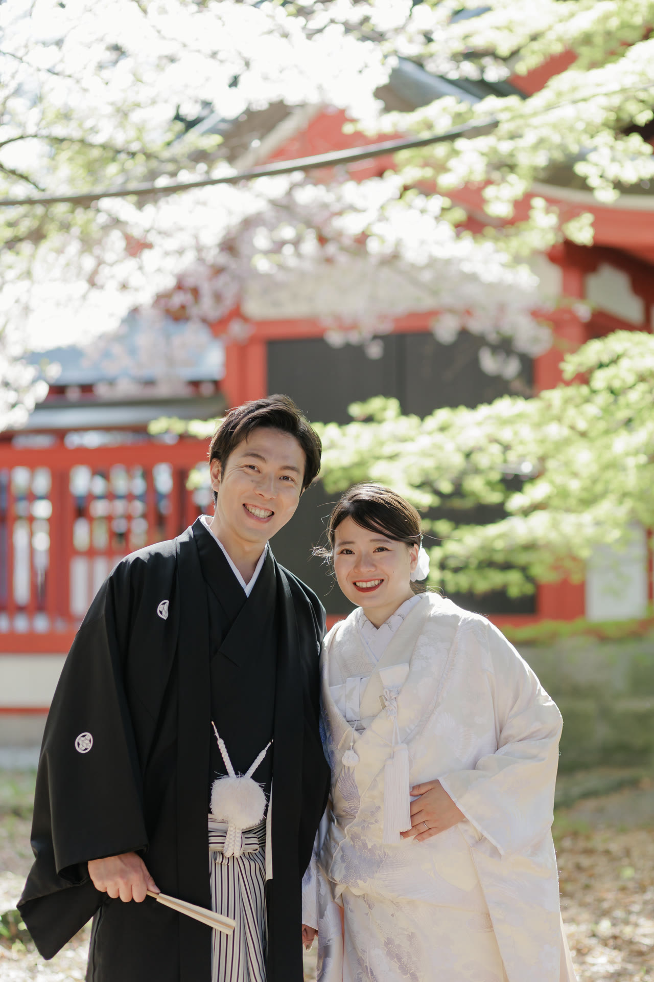 Smiling couple in kimono in front of a shrine hall in spring