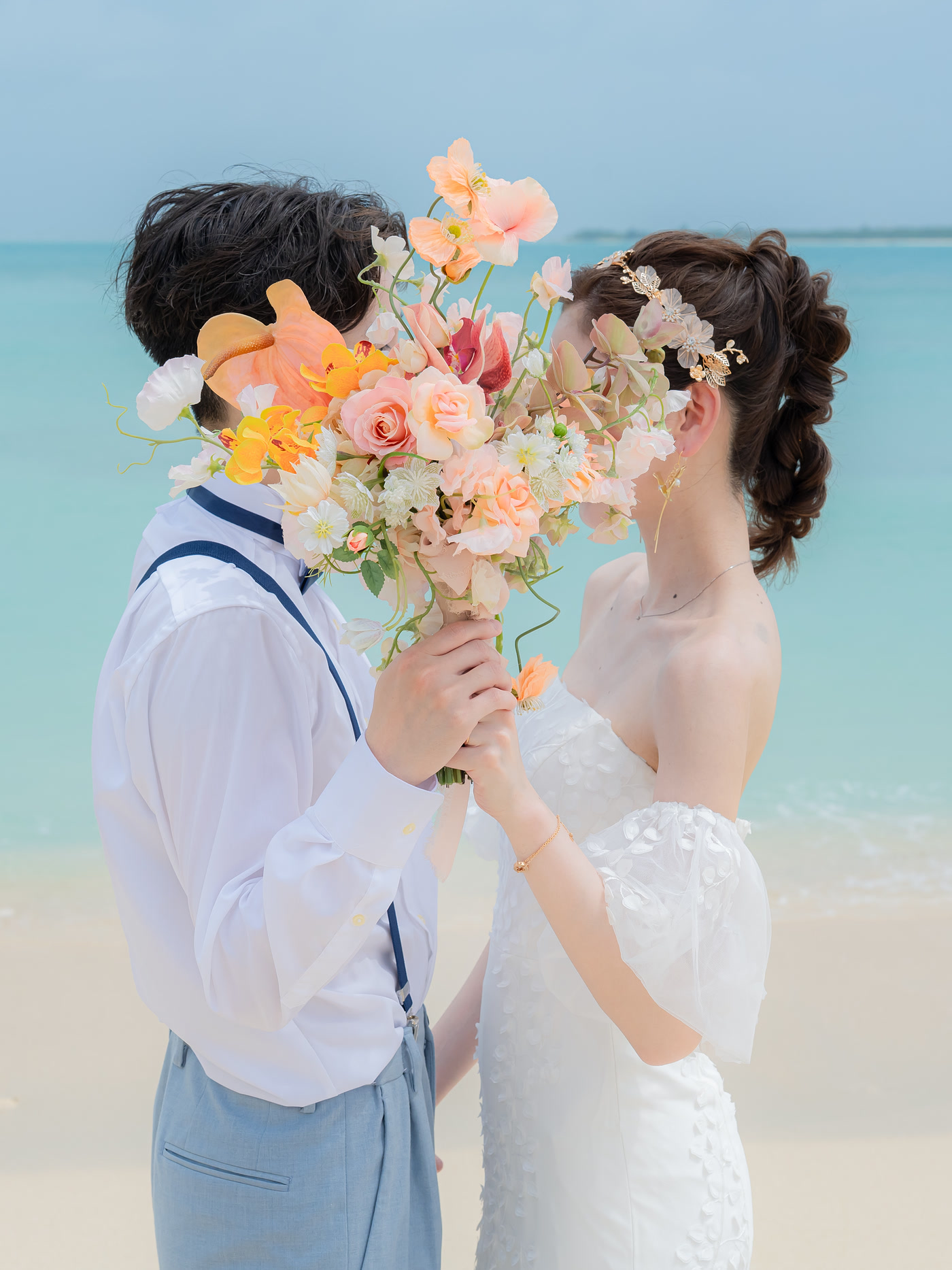 Couple sharing a quiet moment behind a bouquet on an Okinawa beach