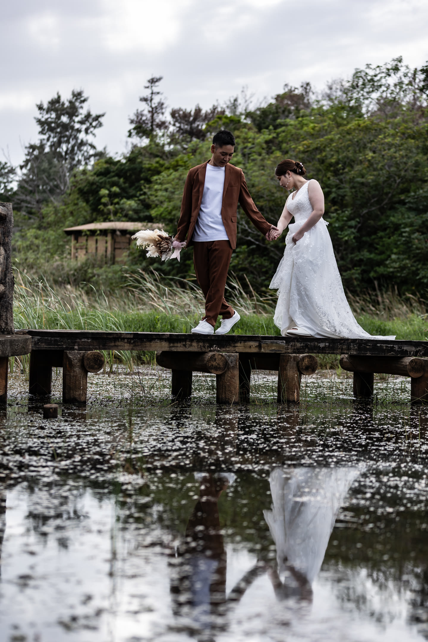 Couple walking a wooden boardwalk over water in Okinawa