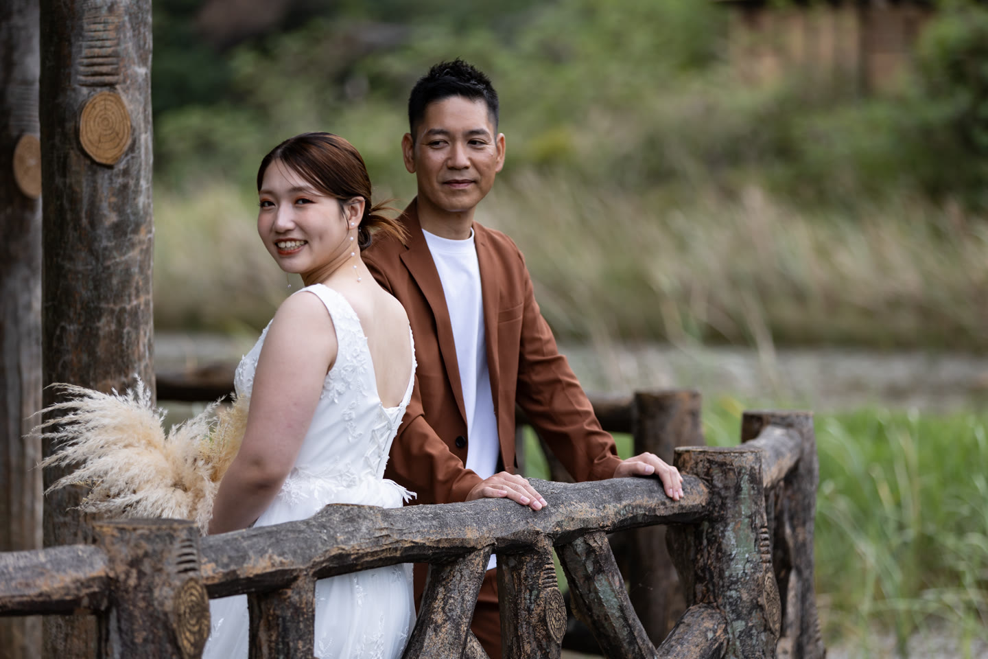 Couple resting on a wooden rail above the water in Okinawa