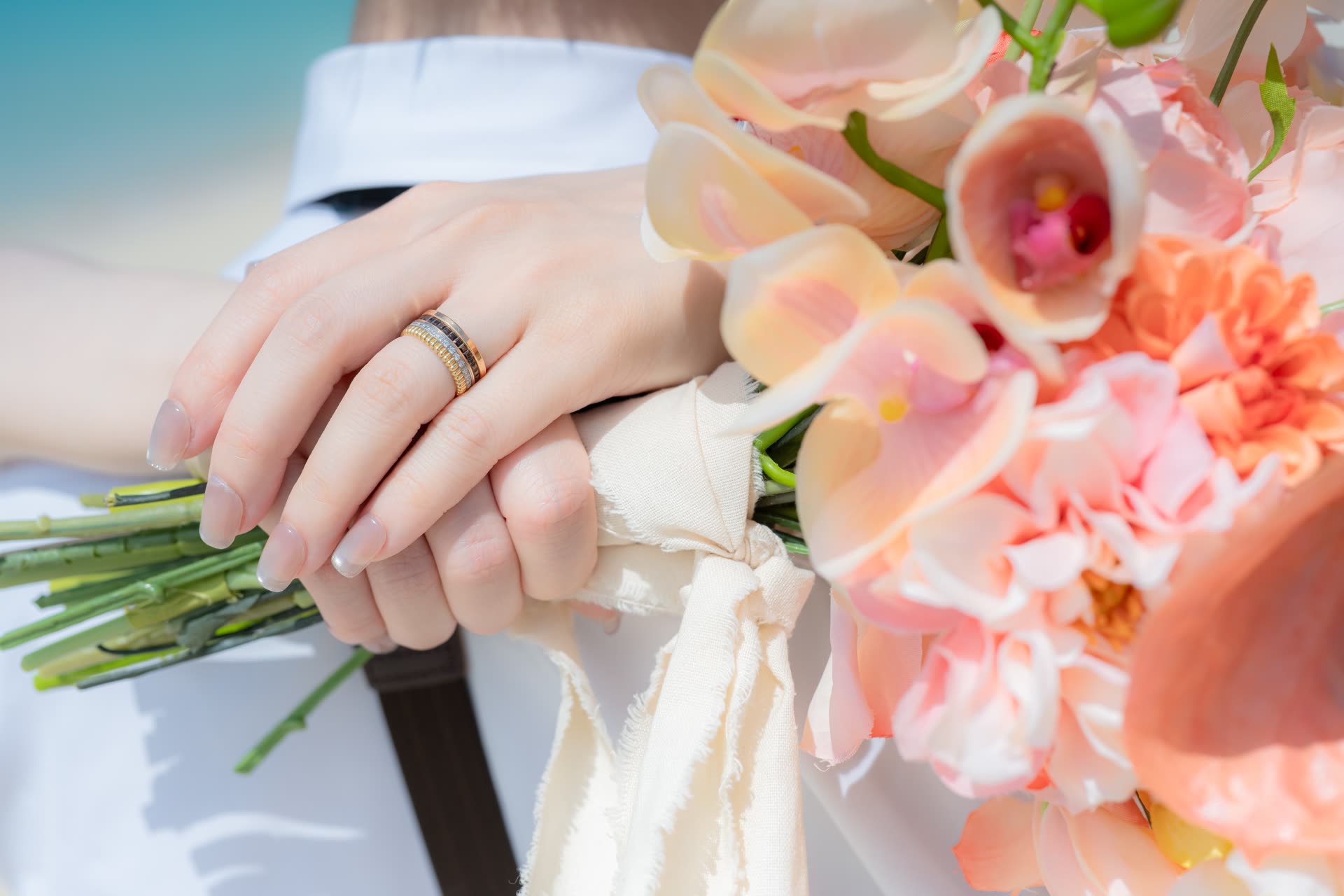 Hands resting on a coral and cream bouquet during an Okinawa pre-wedding shoot