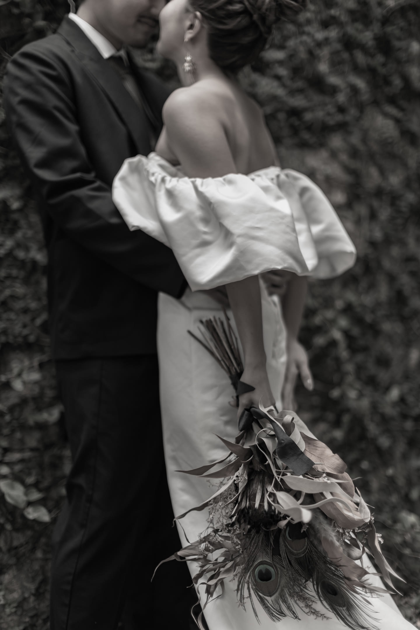 Bride turned away as the groom holds her, against a dark background