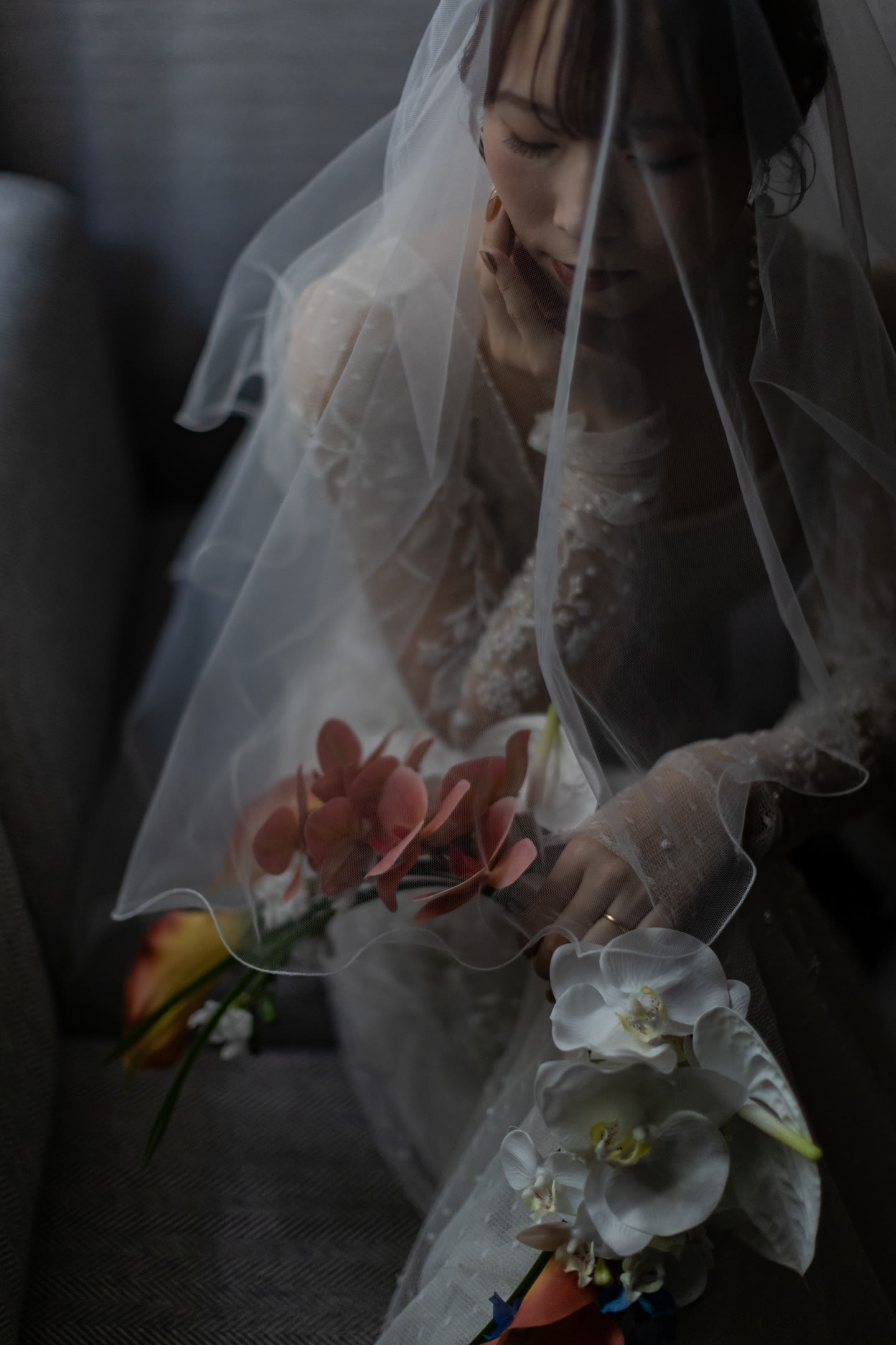 Bride beneath a veil holding her bouquet