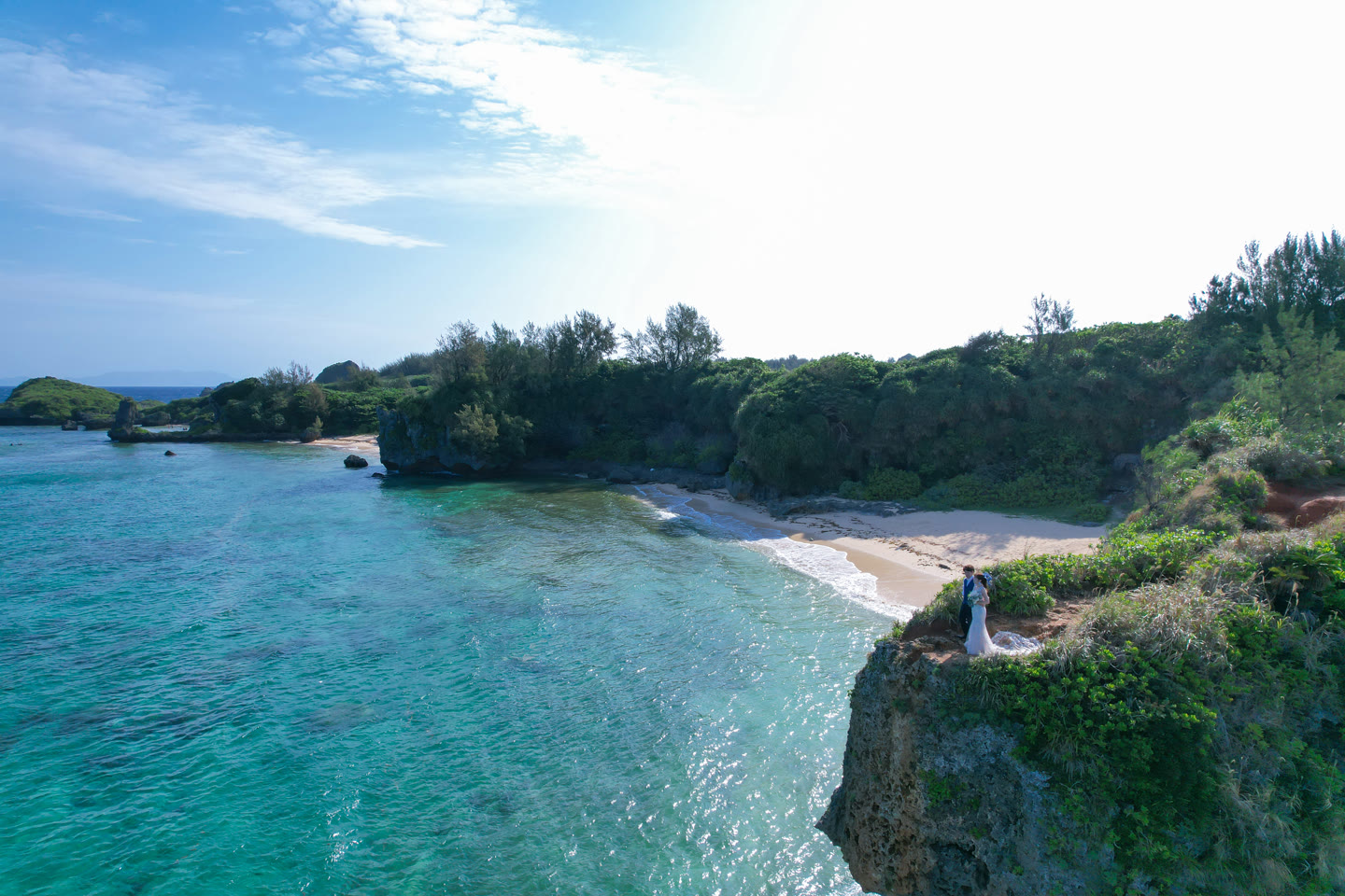 Couple on a cliff above a turquoise cove on the Okinawa coast during a pre-wedding photoshoot