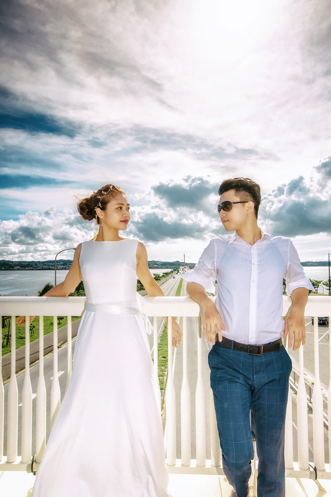 Bride and groom beside a white railing overlooking the Okinawa coast