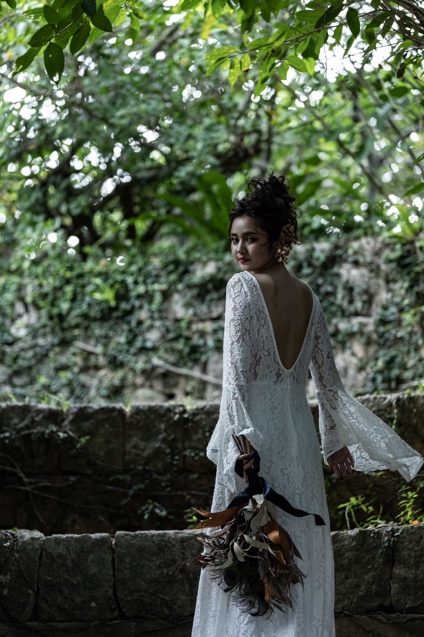Bride seen from behind beside a Ryukyu limestone wall in Okinawa