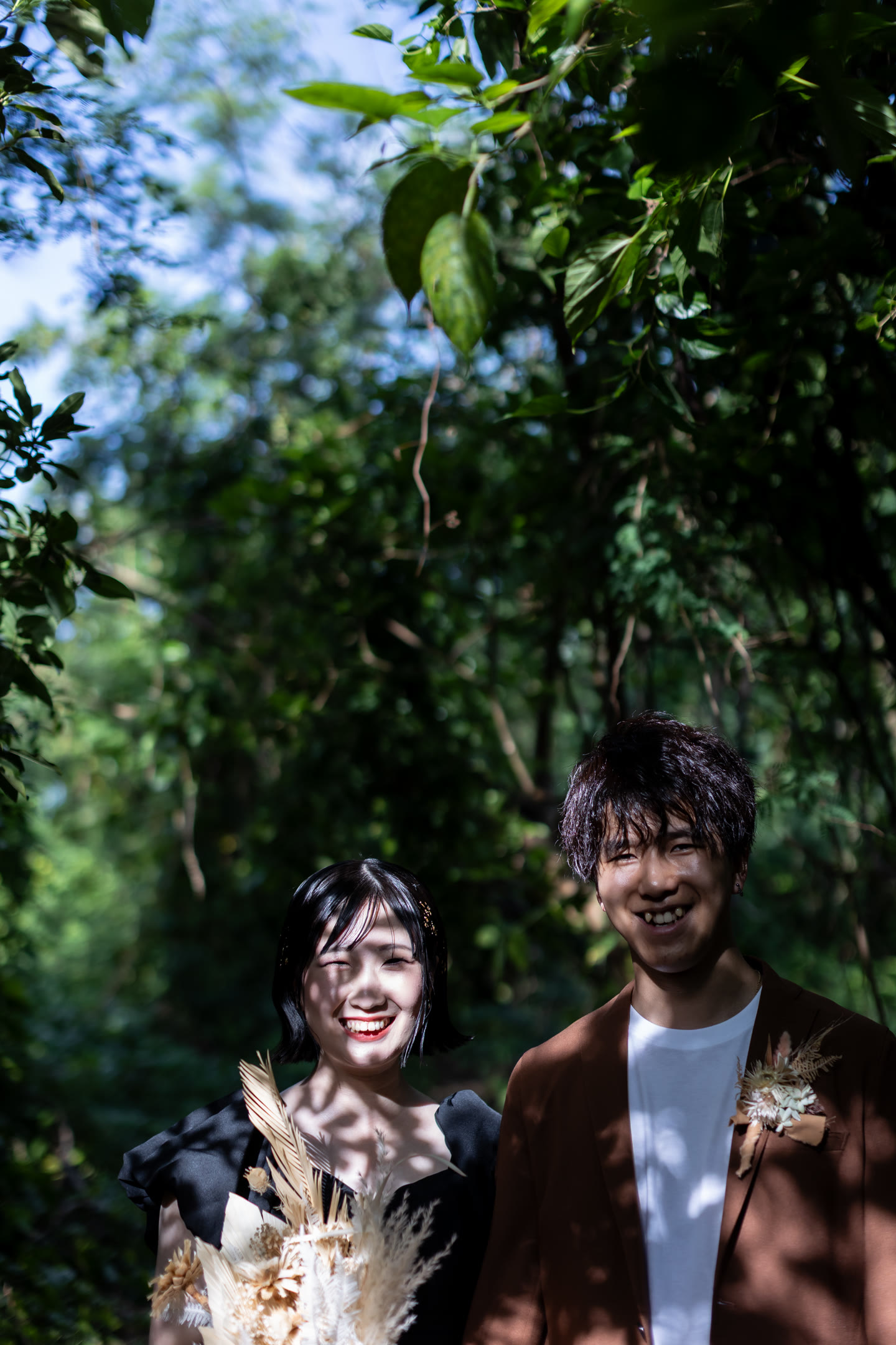 Couple laughing together surrounded by dense green foliage