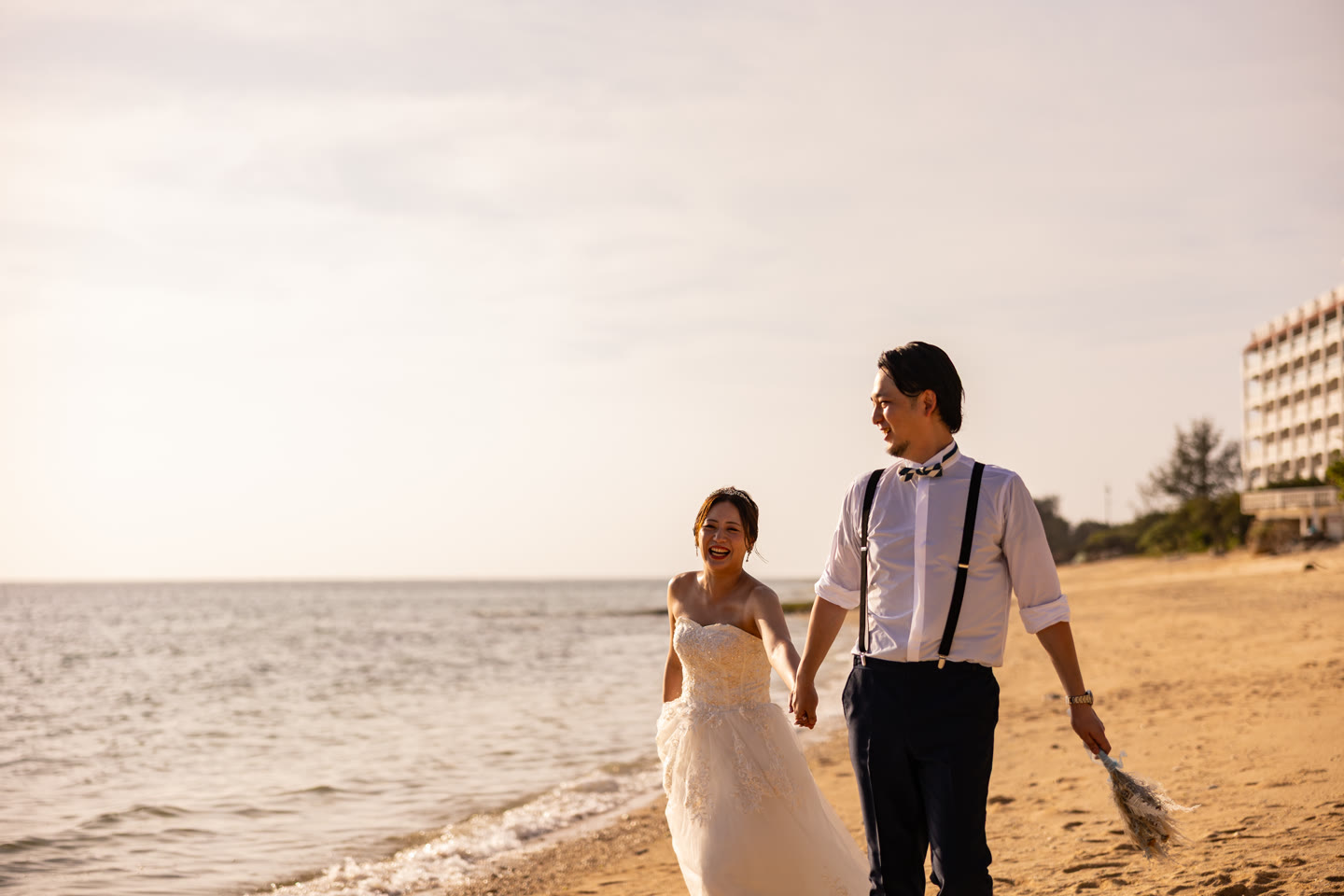 Couple walking an Okinawa beach hand in hand in evening light