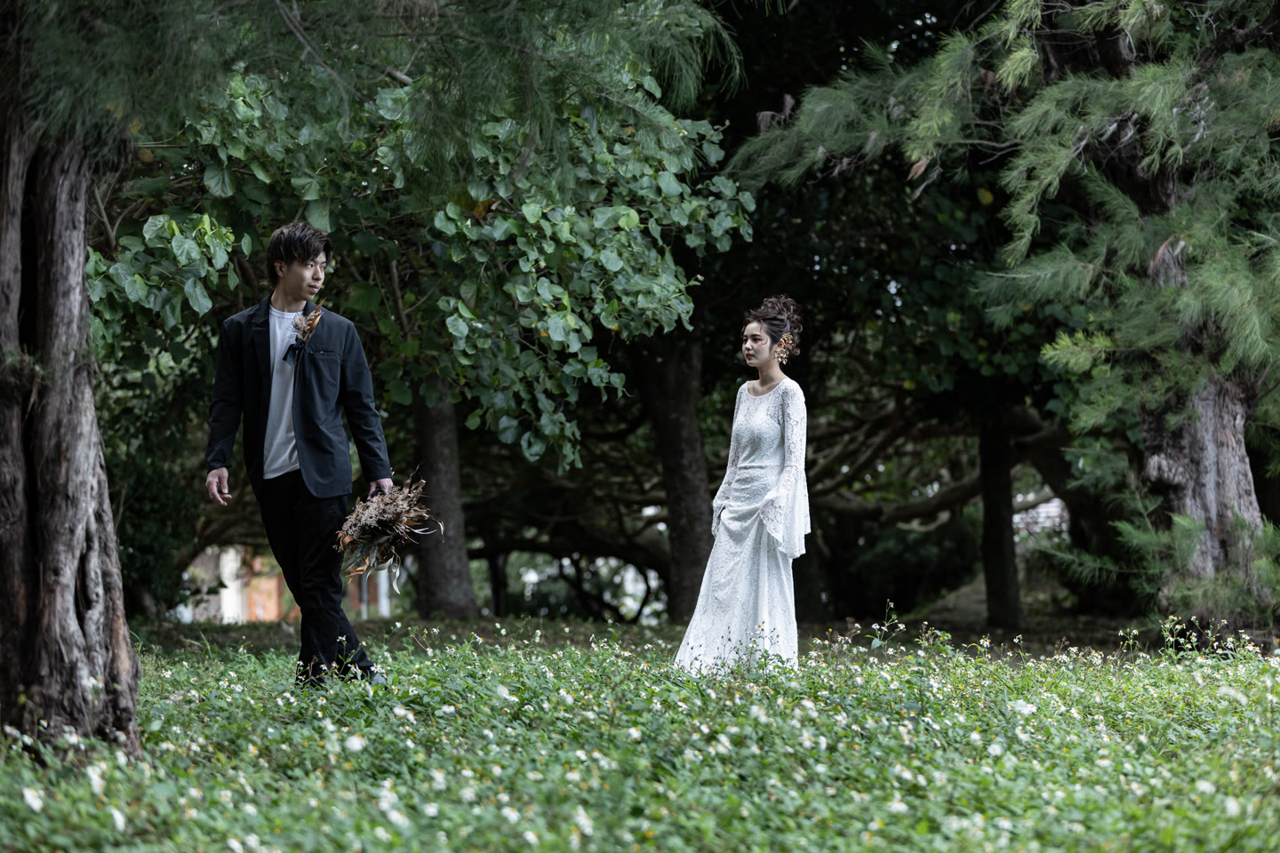 Couple standing apart in a green forest clearing in Okinawa