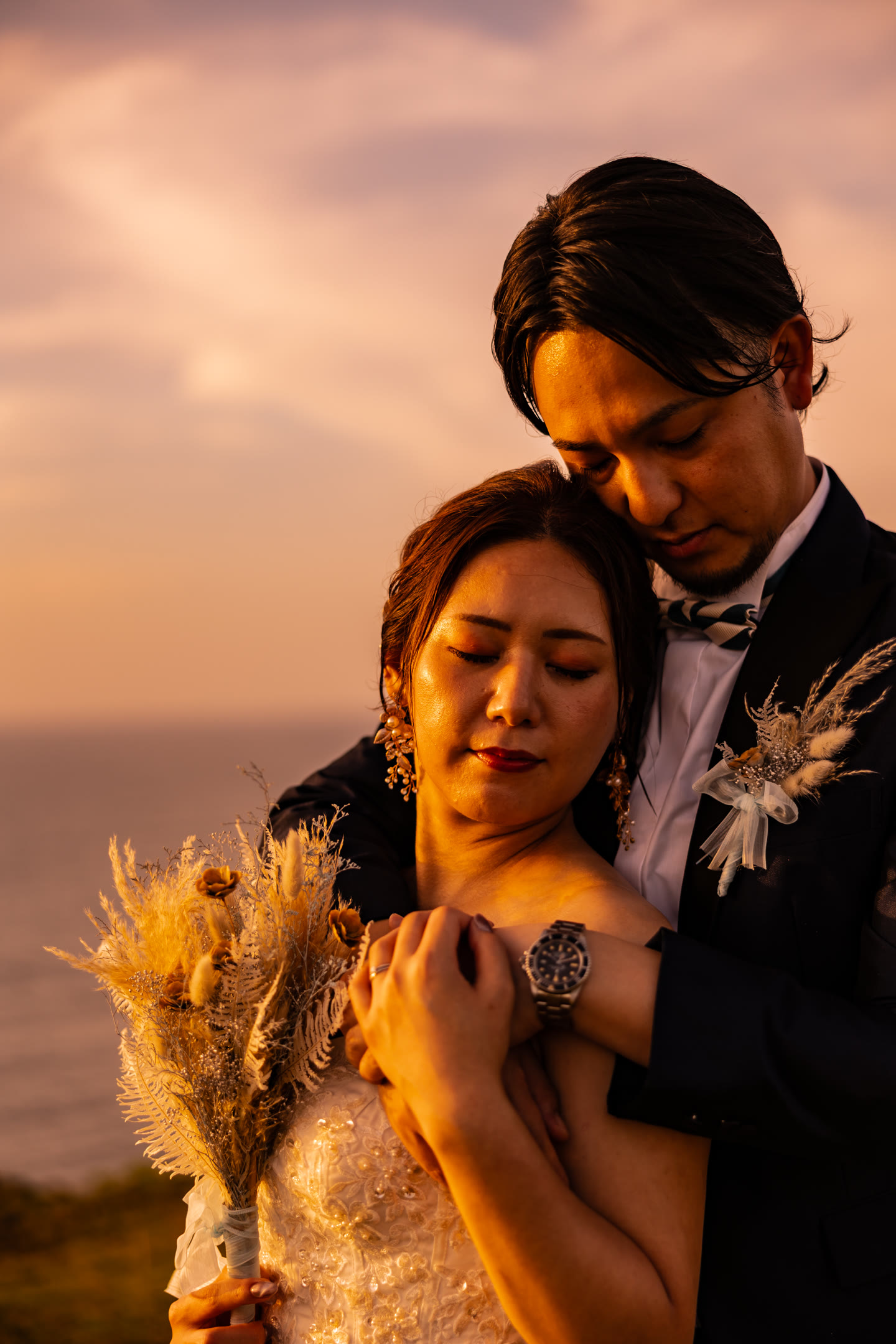Couple close together in golden light, bouquet in hand