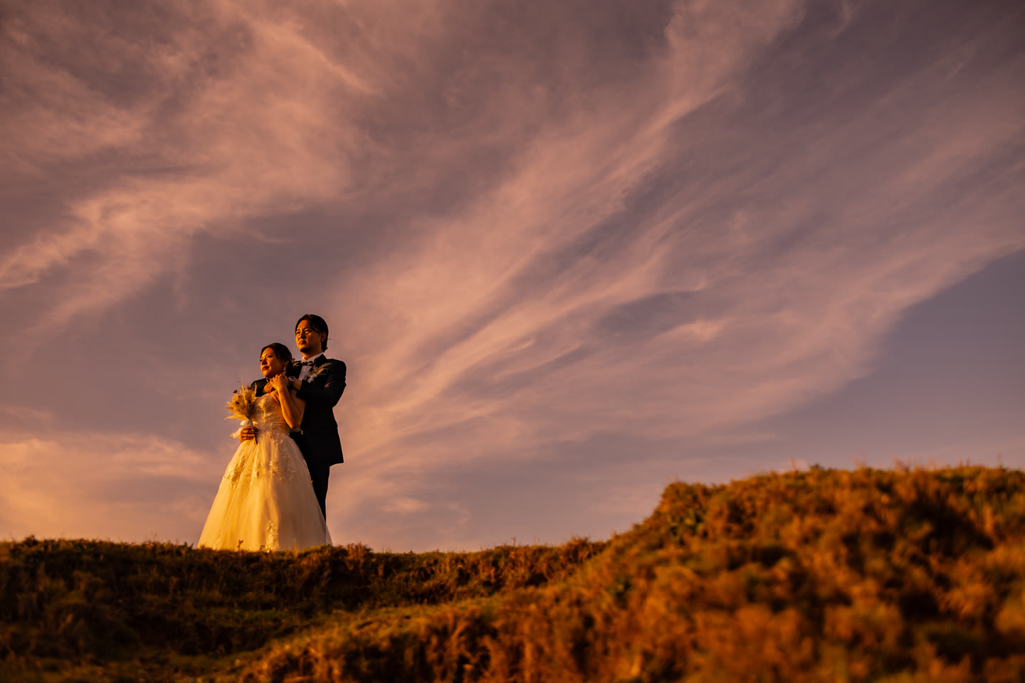 Couple embracing on a hilltop at sunset in Okinawa