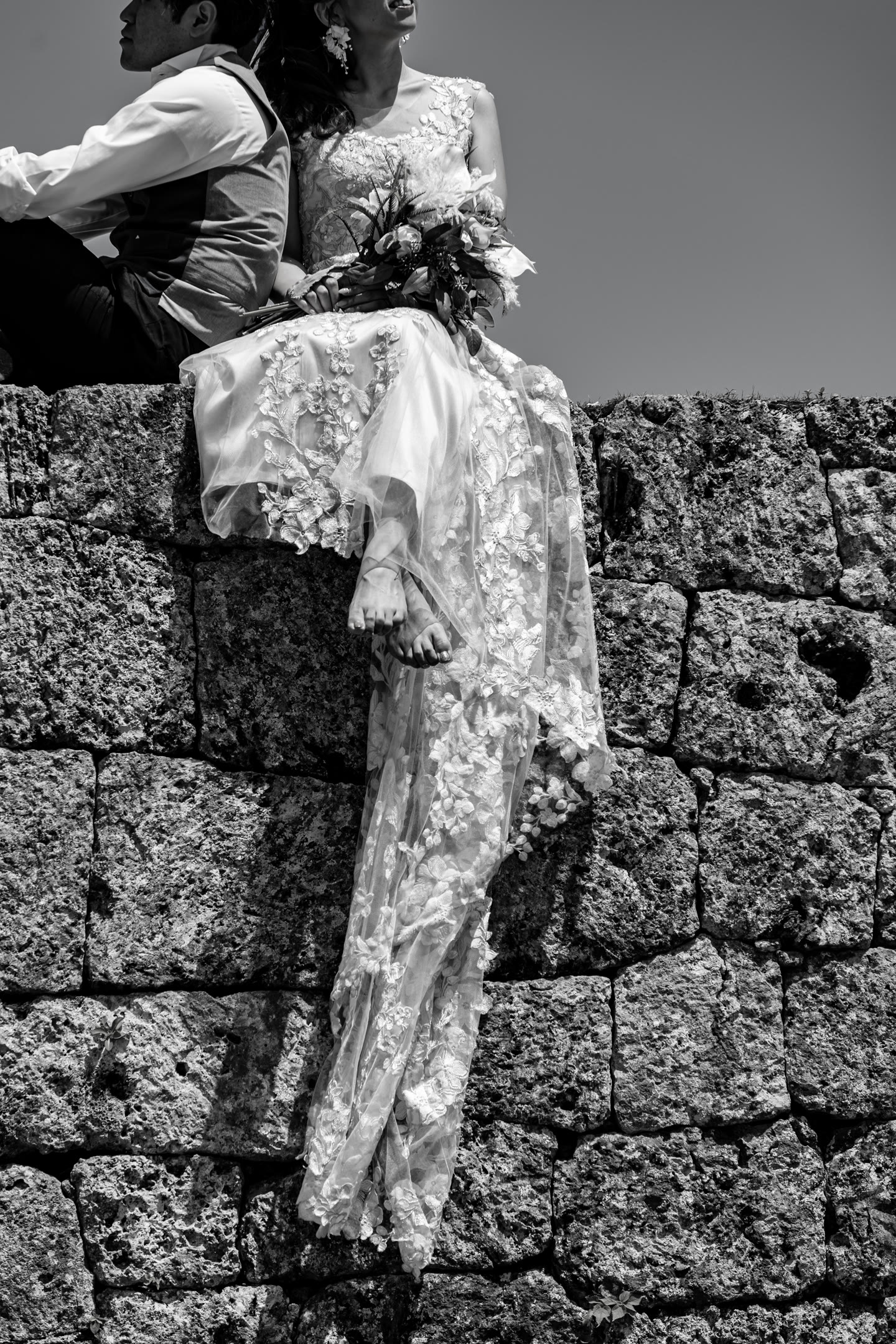 Bride against a limestone wall, photographed in monochrome