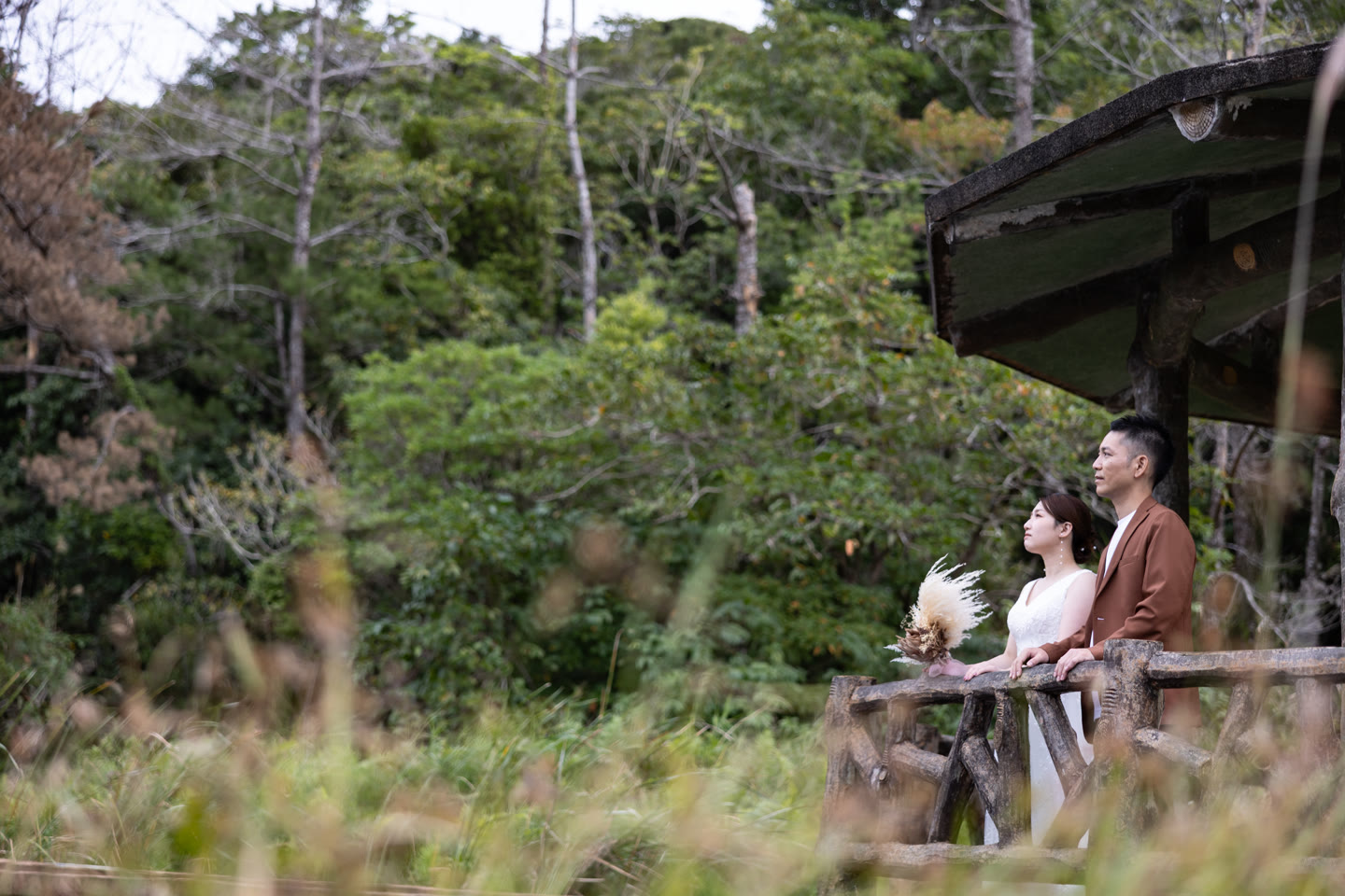 Couple beside a wooden pavilion at the water's edge in Okinawa