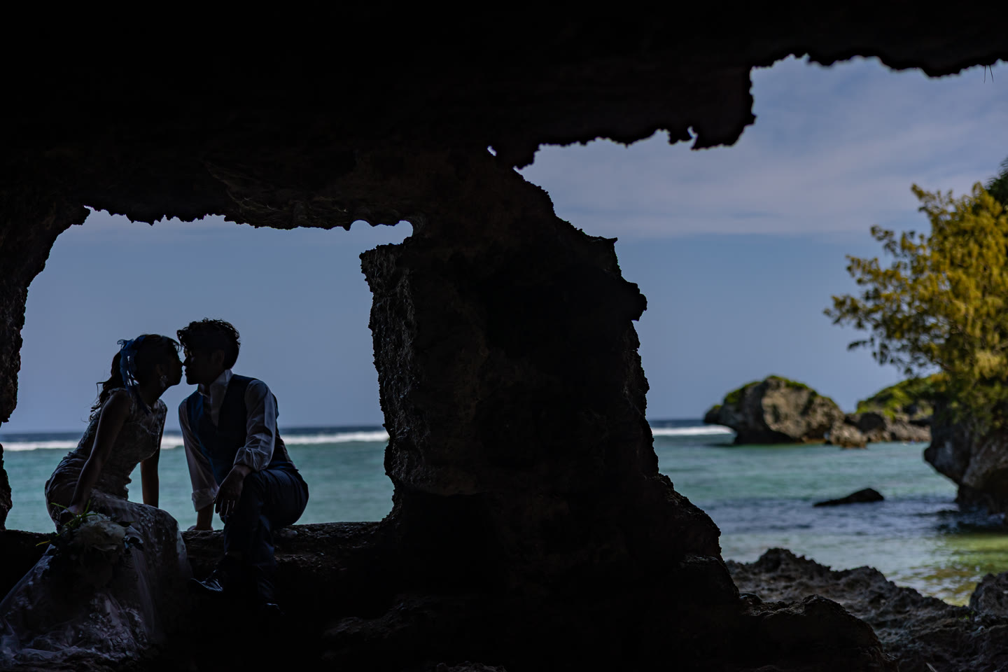 Couple framed by the mouth of a sea cave on the Okinawa coast