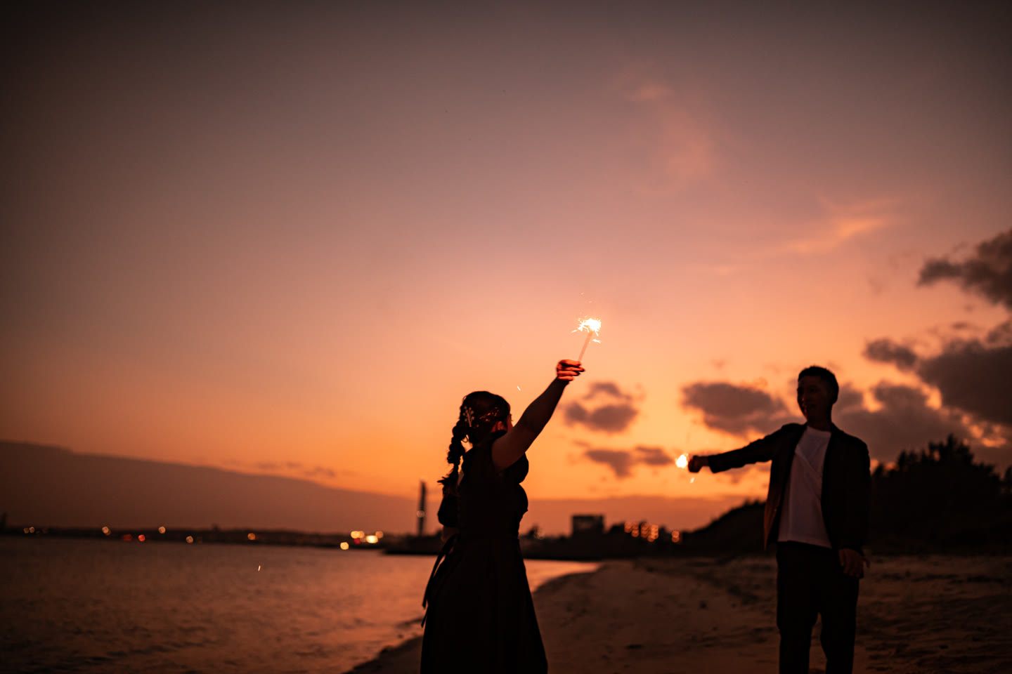 Sparklers lighting a couple on the Okinawa shoreline after sunset