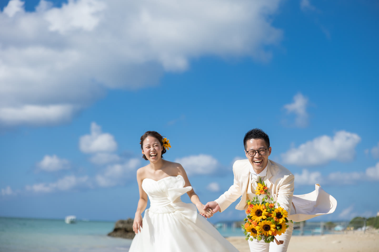 Couple holding a sunflower bouquet on an Okinawa beach under a blue sky