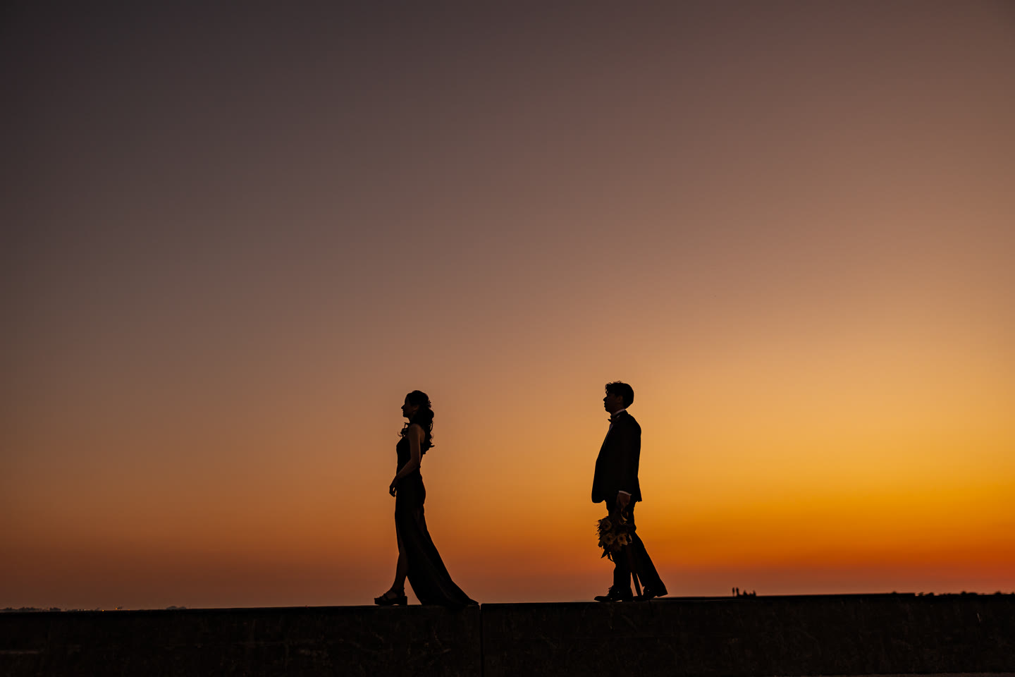 Two silhouettes walking against a graduated sunset sky in Okinawa