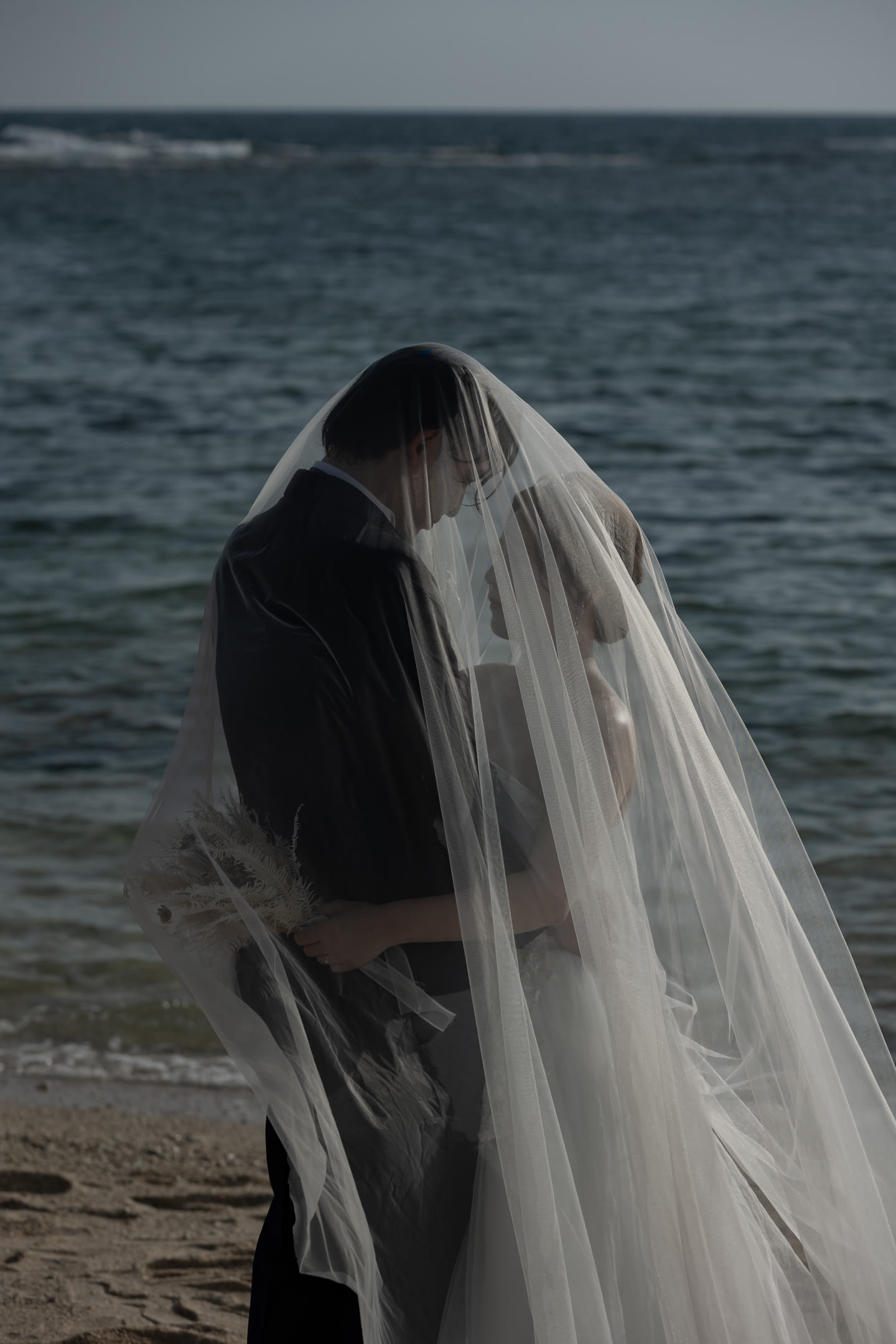 Couple photographed beneath a sheer veil