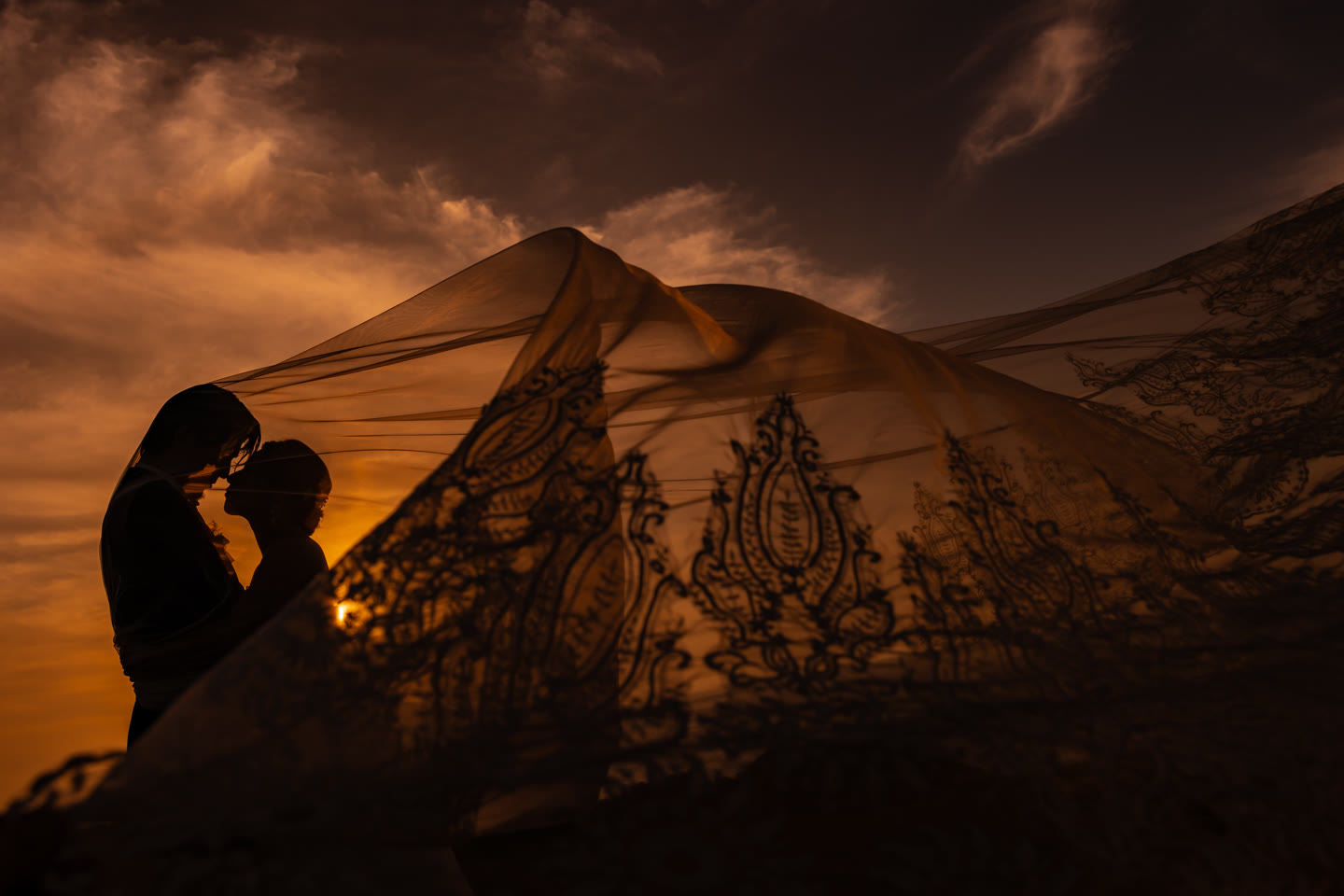 Bridal veil sweeping across a sunset sky in silhouette in Okinawa