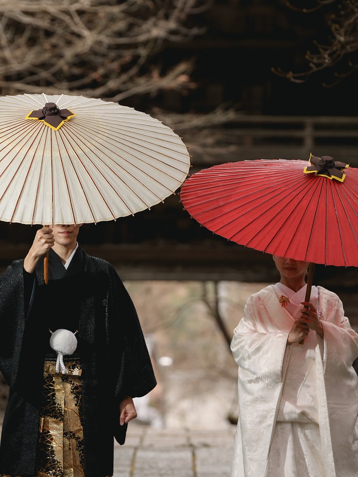 Couple in formal Japanese wedding attire photographed with paper umbrellas