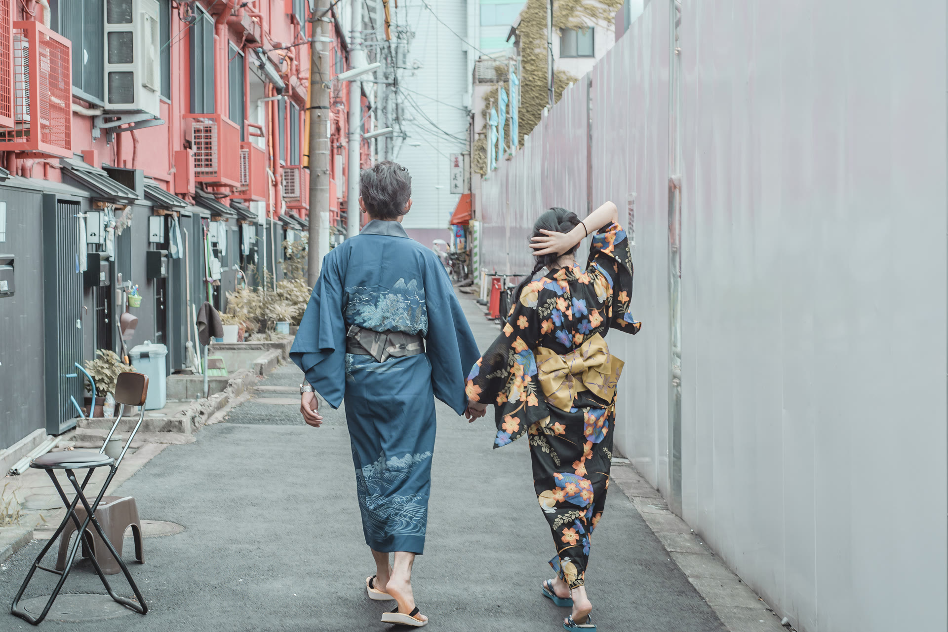 Couple in kimono walking hand in hand down a quiet Tokyo back street