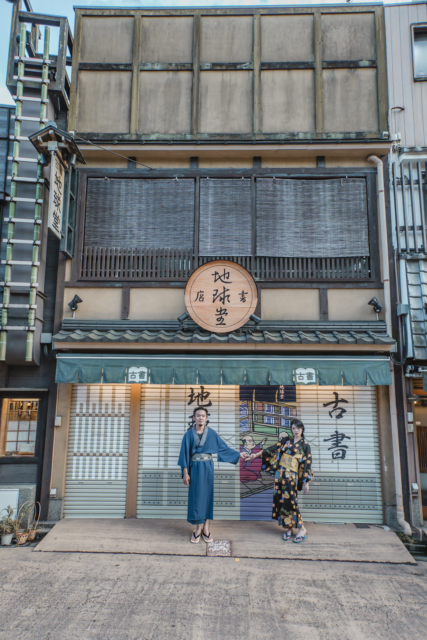 Couple in kimono in front of a wooden second-hand bookshop in Tokyo