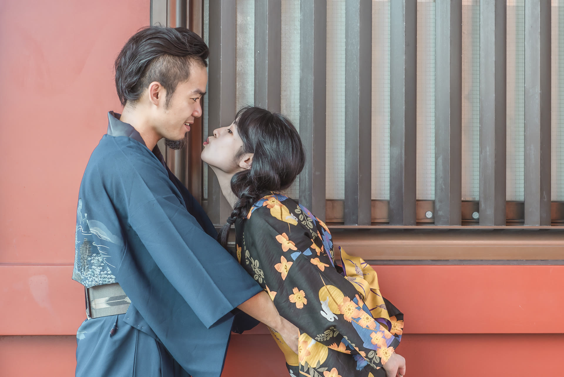 Couple in kimono against a red shrine wall in Asakusa