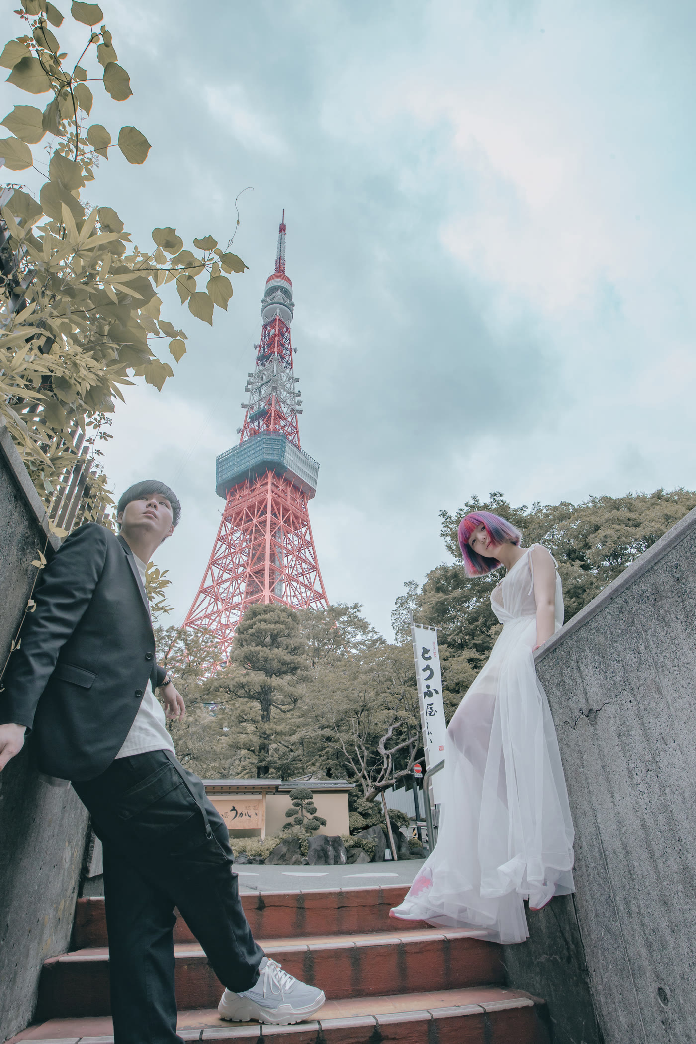 Couple standing together with Tokyo Tower rising through the trees
