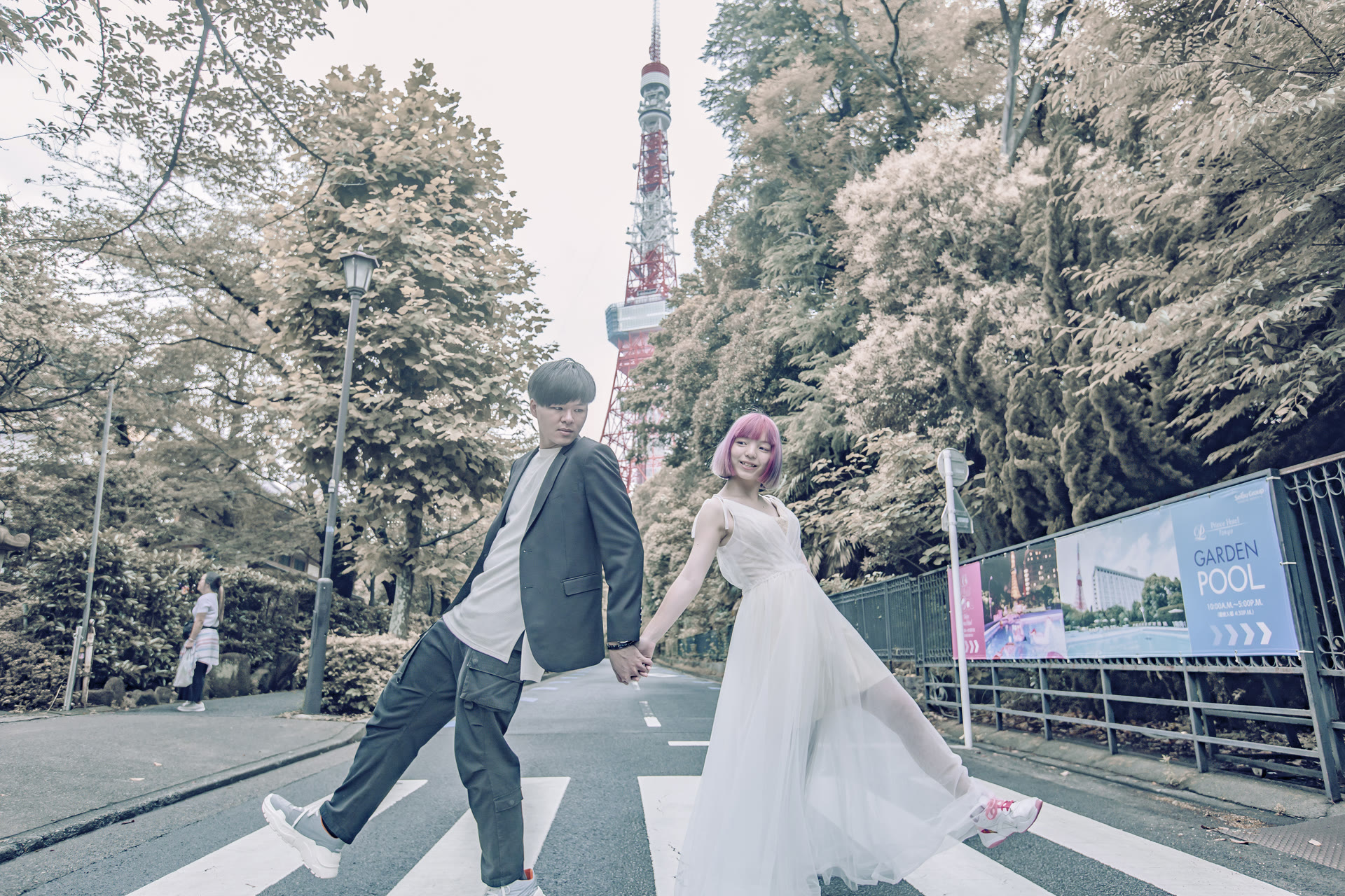 Couple crossing a Tokyo street in a white gown and suit with Tokyo Tower behind them